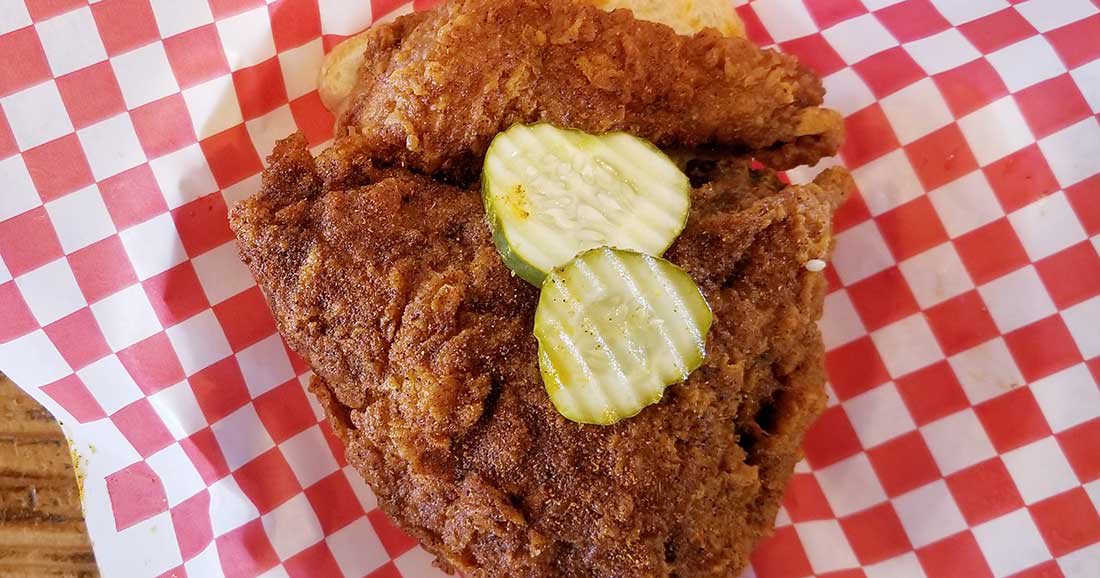 Chicken sandwich topped with pickles and sitting in a platter