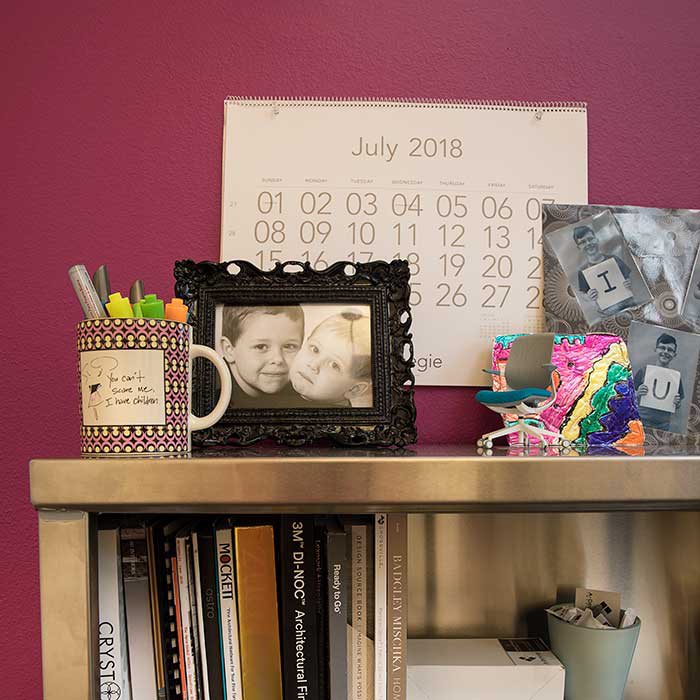 books line the bottom row of her shelves while the top is filled with photos, gifts, and items of sentimental value