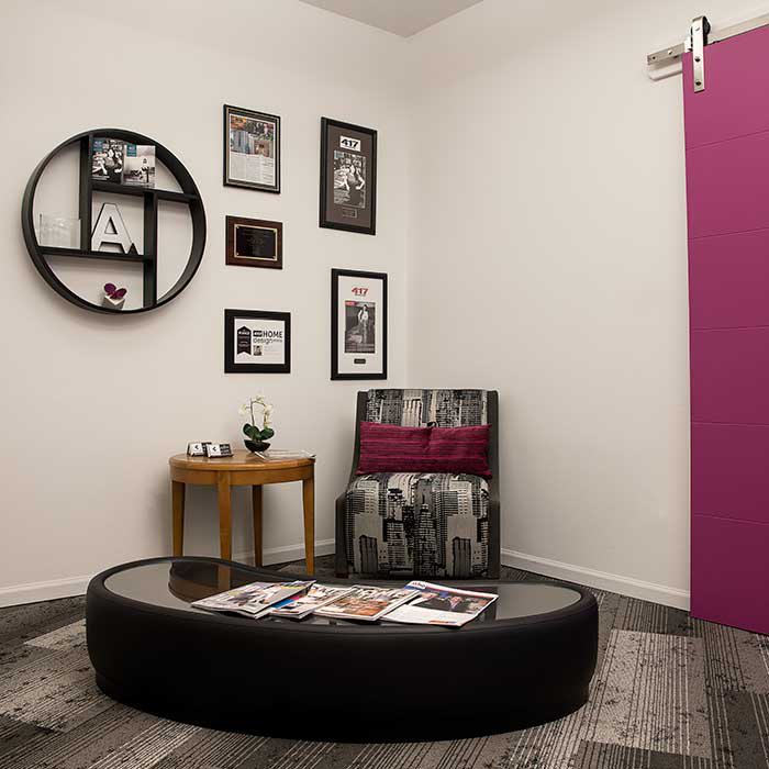 circular desk, chair, side table sit in the corner of the room with awards framed on the wall