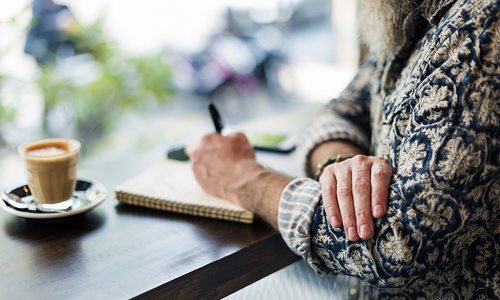 a man journaling at a coffee shop