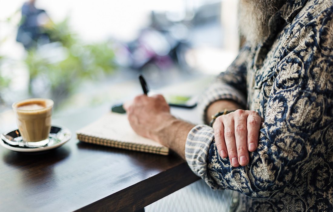 man journaling at a coffee shop