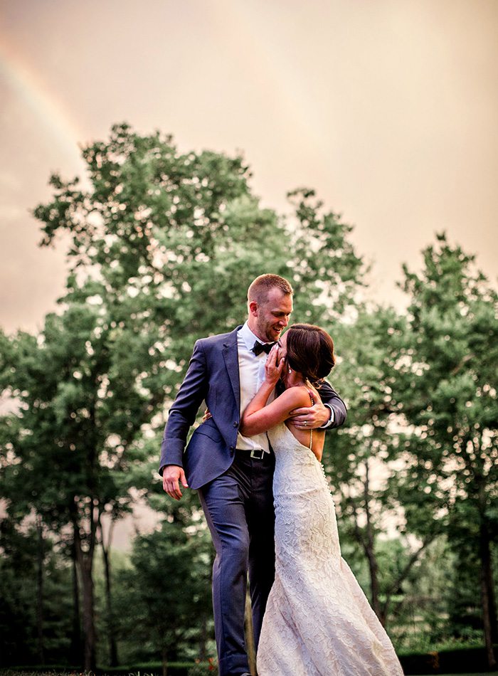 wedding couple standing in front of a rainbow