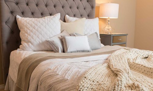 bed neatly made with variety of pillows and blankets