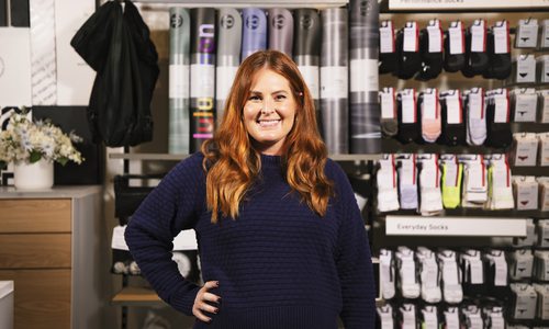 lululemon manager Annie Ratliff poses in front of a yoga mat display inside the store.