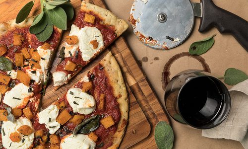 pizza and pizza cutter on cutting board