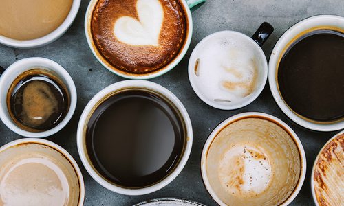 A barista pours milk into a cappuccino