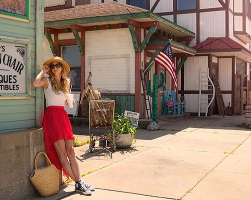 a woman leans against a store front