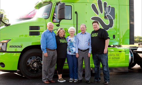 people standing in front of a bright green semi truck