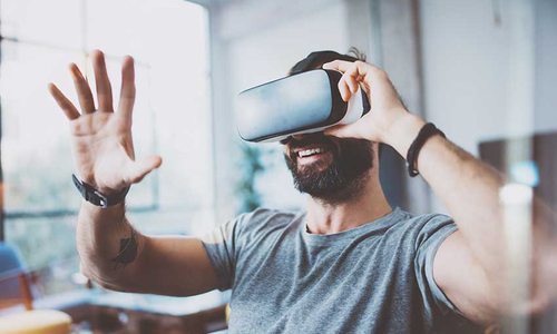 A man places a hand in front of his face as he looks through virtual reality googles