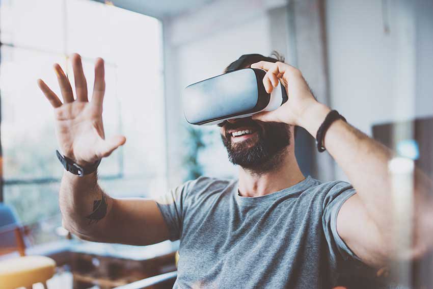 A man places a hand in front of his face as he looks through virtual reality googles