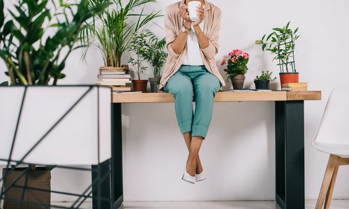 Woman sitting on desk with office plants